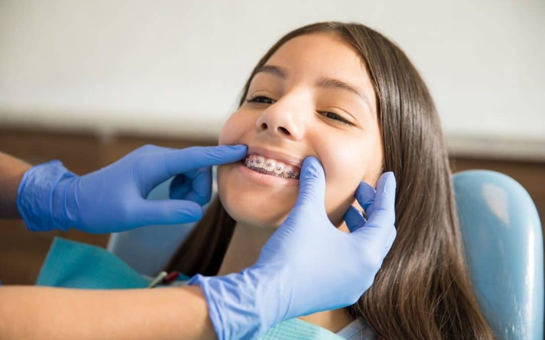 Orthodontist examining patient's clear braces during dental checkup in San Antonio.